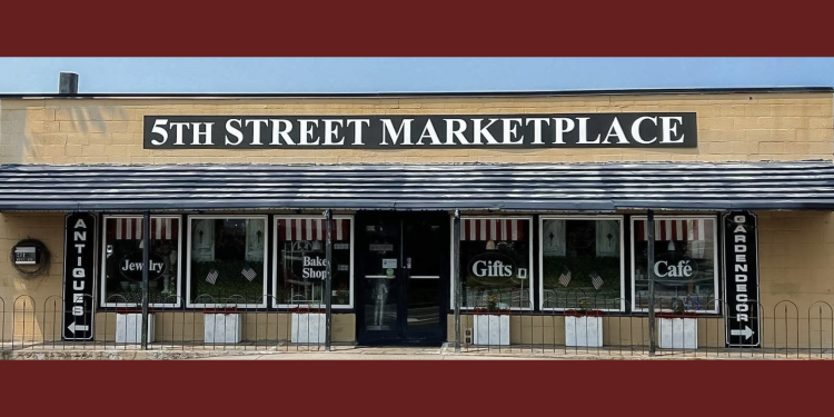 Exterior view of 5th Street Marketplace featuring signs for antiques, jewelry, baked goods, gifts, and a café.